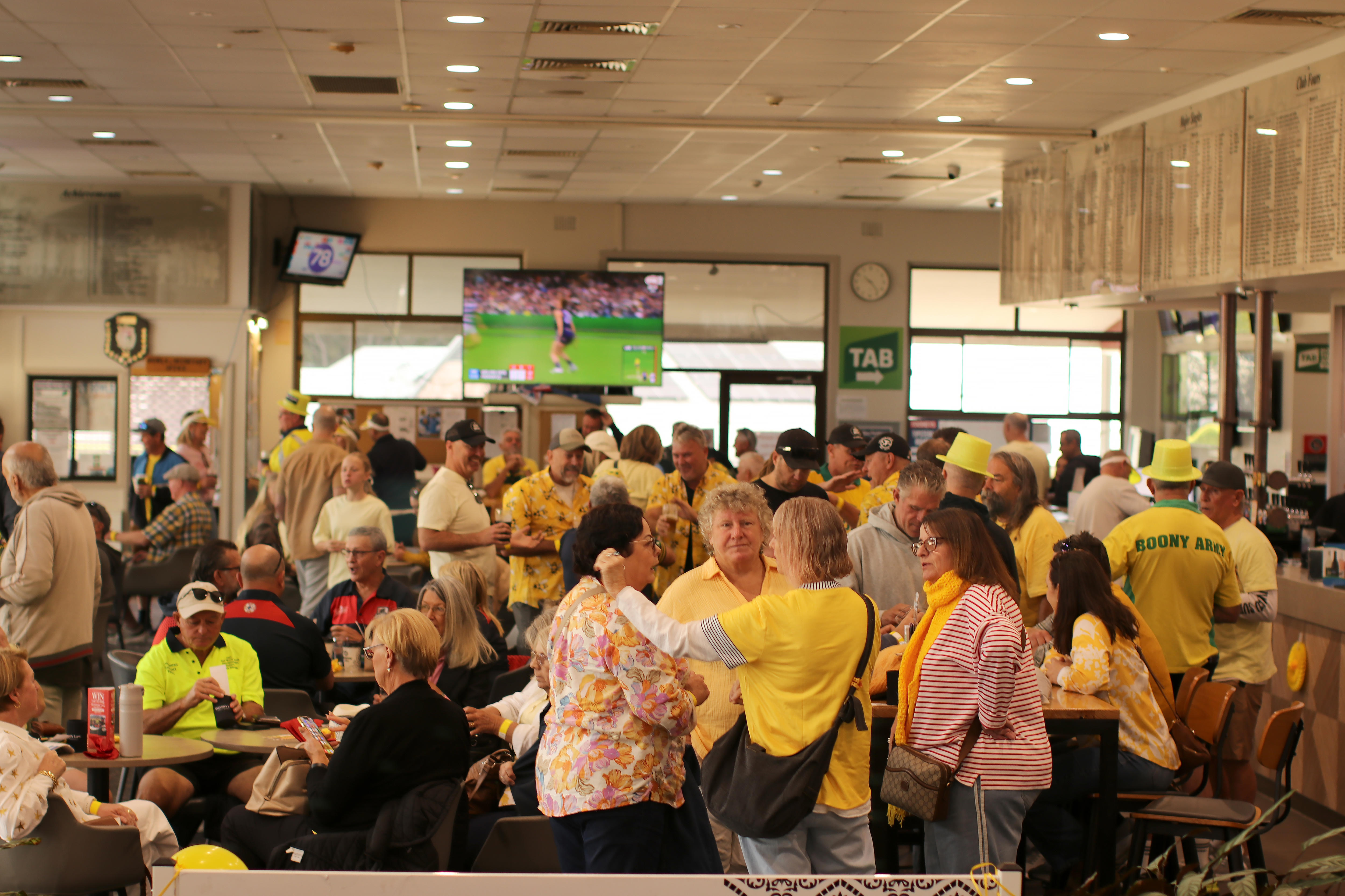 More than 200 people in a room, most wearing yellow.
