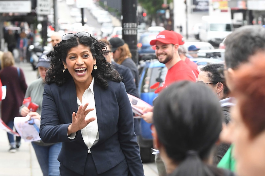 On a crowded street, the Greens leader smiles and waves.