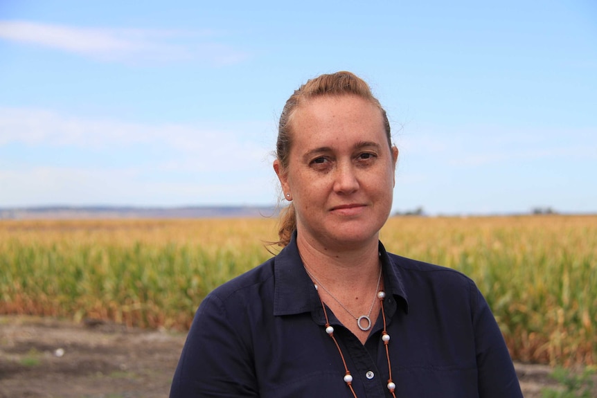 A woman stands in front of a paddock of sorghum.
