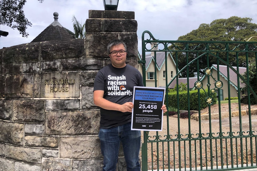 A man holding a sign out side of the Prime Minister's residence in North Sydney.