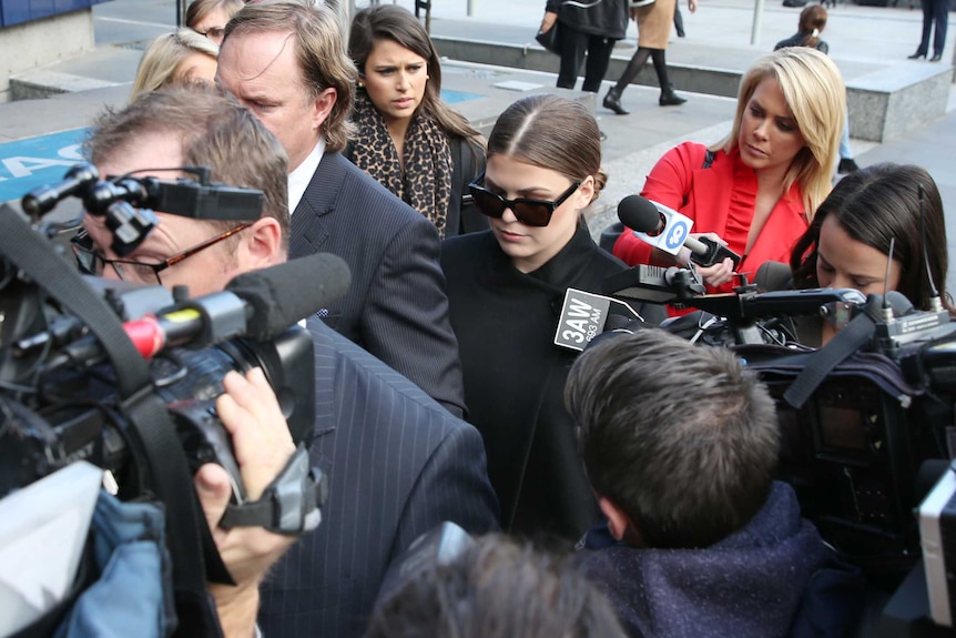 Belle Gibson leaves court in Melbourne surrounded by TV cameras and journalists.