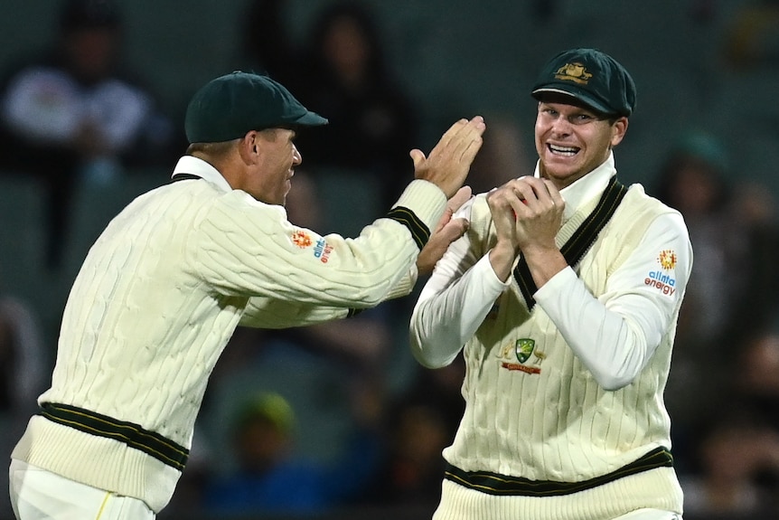 Steve Smith grins and holds his hands to his chest as David Warner comes to him and raises his hand in front of him