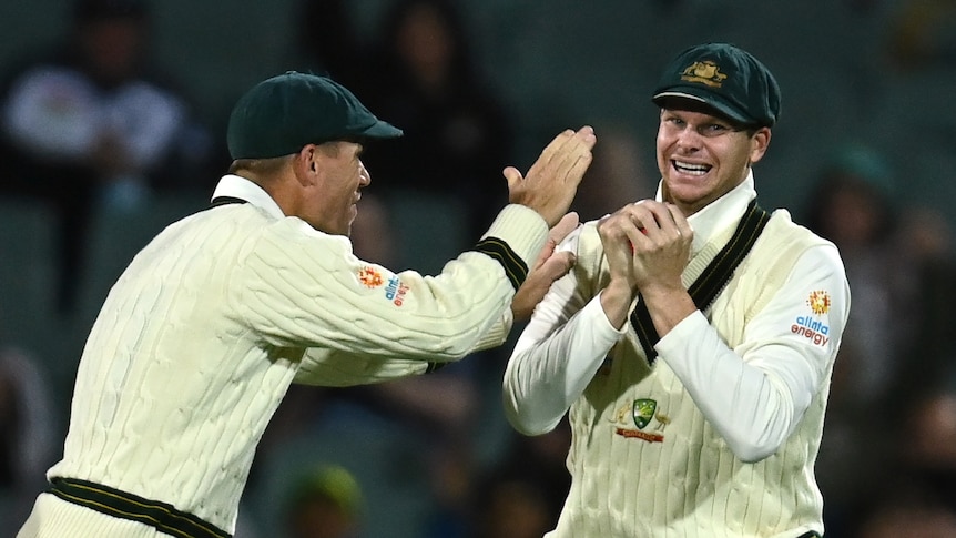 Steve Smith grins and holds his hands to his chest as David Warner comes to him and raises his hand in front of him