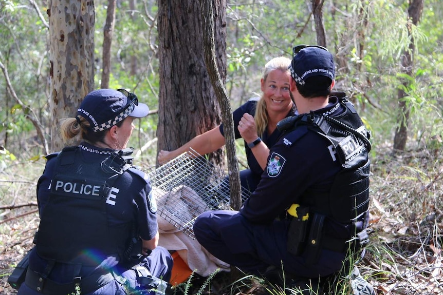 RSPCA nurse Kristen and constable Finegan and Bray crouch near tree after releasing a koala.