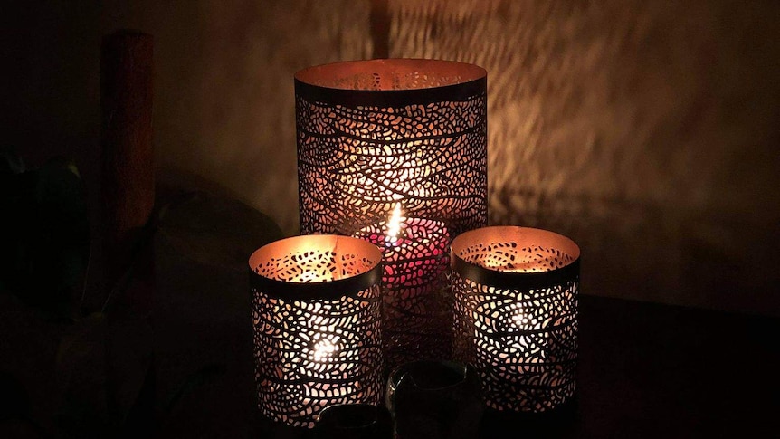 three leaf design candle holders lit up with candles. There are two small and one large.