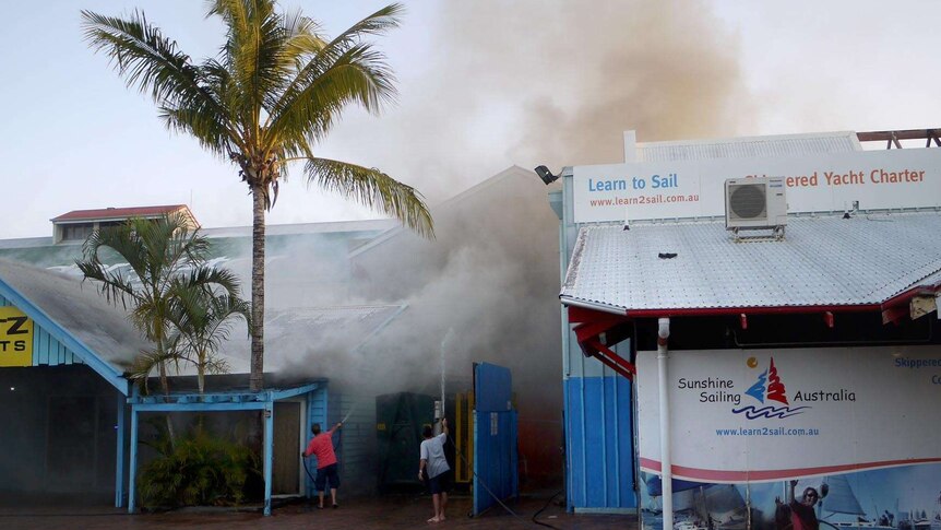 Two people use garden hoses to douse a fire at Underwater World.
