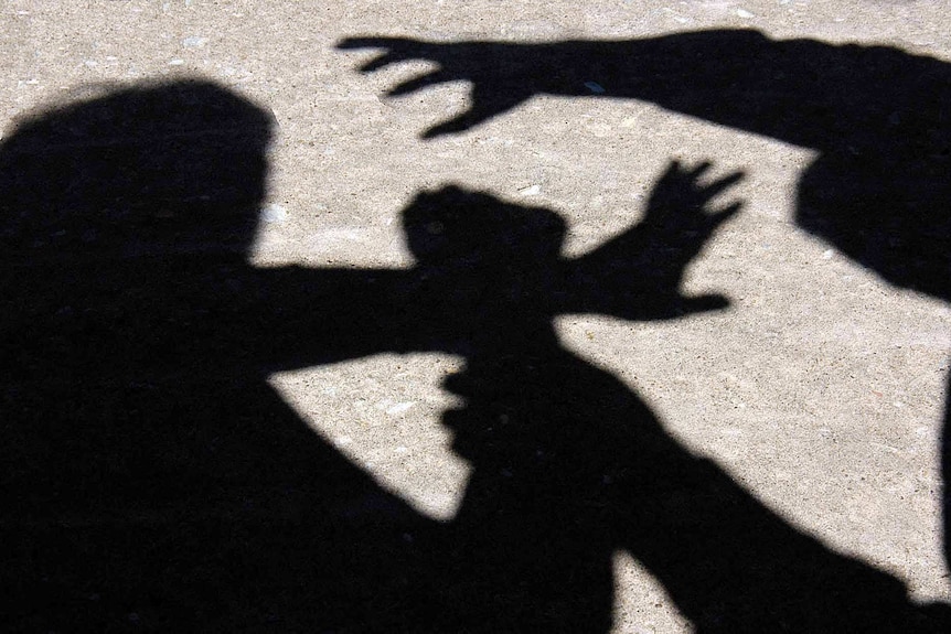 A man grabs a woman's arm through a silhouette on the ground.