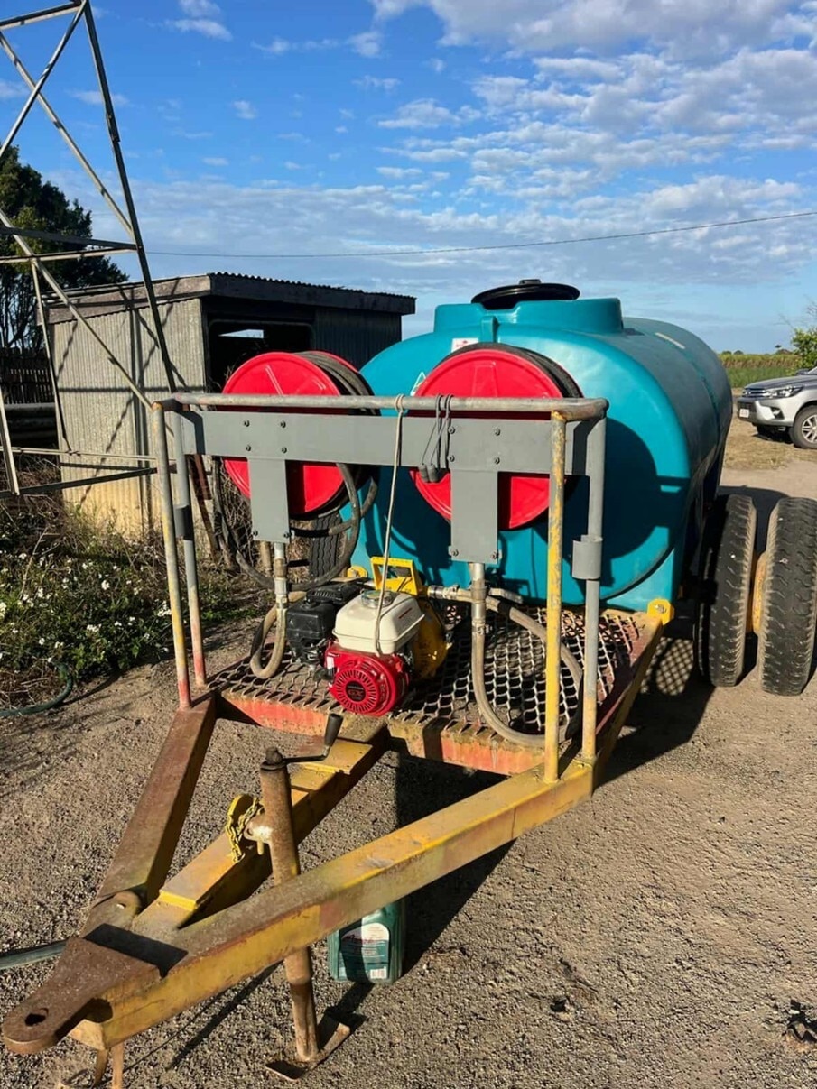 Un gran tanque de agua en un remolque estilo ute con conexiones para mangueras.