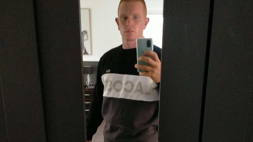 Jake Opacic takes a selfie. He has a full leg tatoo, ginger hair and wears shorts.