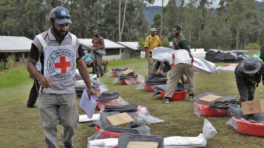 Red cross workers check aid kits laid out on the grass