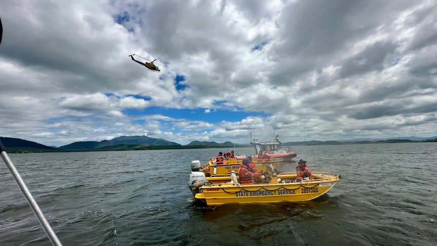 Two emergency boats on a dam, over which flies a rescue helicopter.