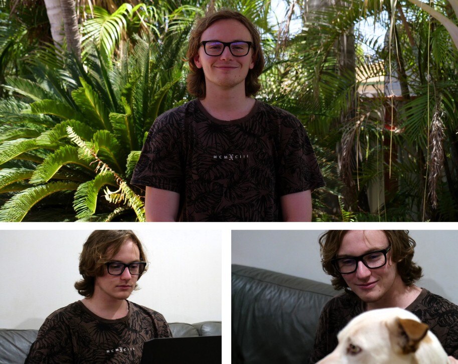 A young man stands in a leafy garden, pats his dog Dusty and works on his laptop. 