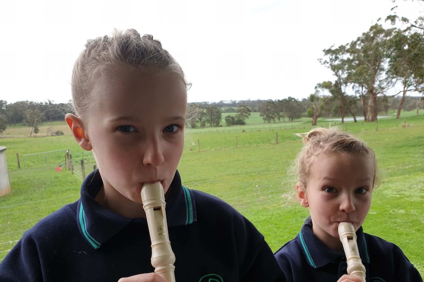 Two young girls playing recorder