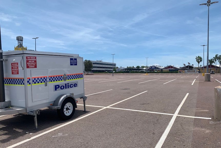 Image of an empty outdoor car park, with a police trailer parked on the left of the image.