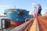 Wide shot of an iron ore ship tied up at Port Hedland dock loaded with ore from Gina Rinehart's Roy Hill mine.