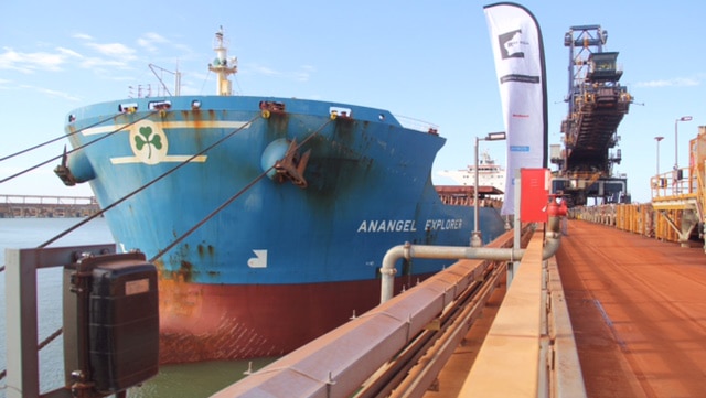 Wide shot of an iron ore ship tied up at Port Hedland dock loaded with iron ore from Gina Rinehart's Roy Hill mine.