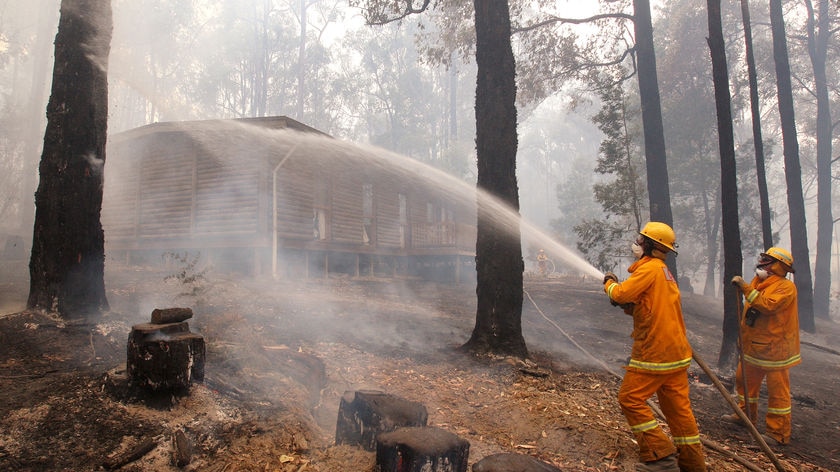 Wide shot of CFA crew hosing down a house in north of Healesville in Victoria on Feb 10, 2009.