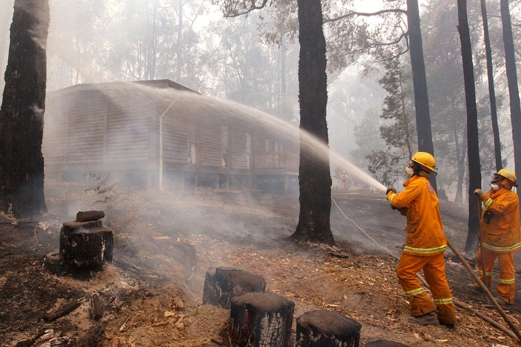 Wide shot of CFA crew hosing down a house in north of Healesville in Victoria on Feb 10, 2009.