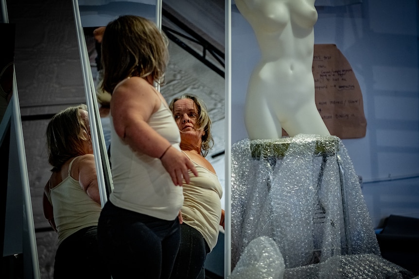 A woman with dwarfism looking at herself in a mirror