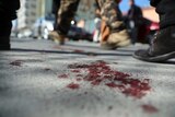 Afghan security personnel walk on a bloodstained road