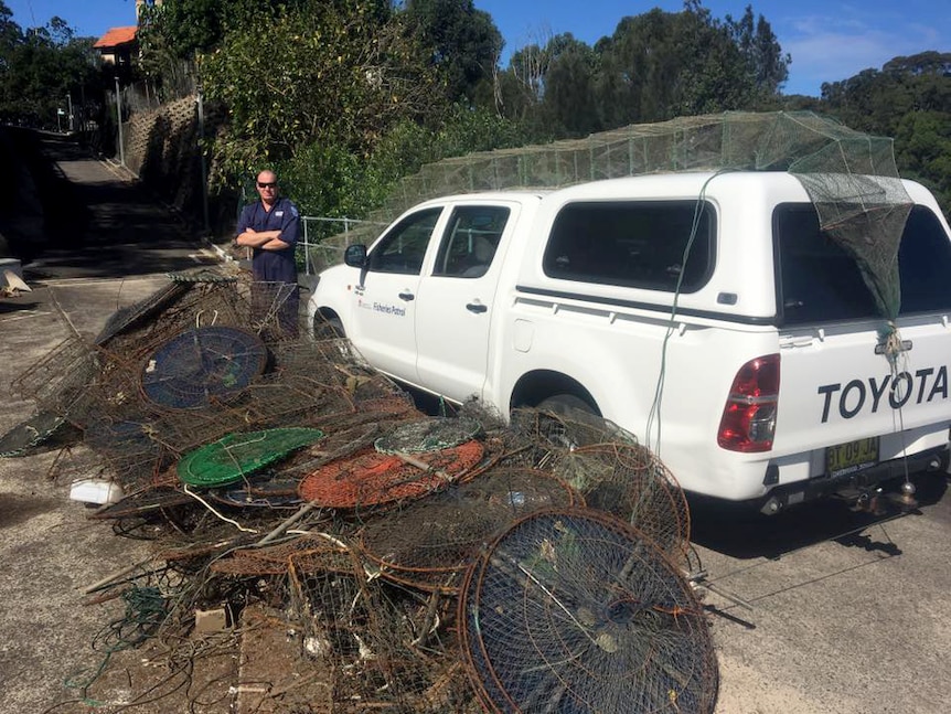 Fisheries officer stands behind stacks of crab traps.