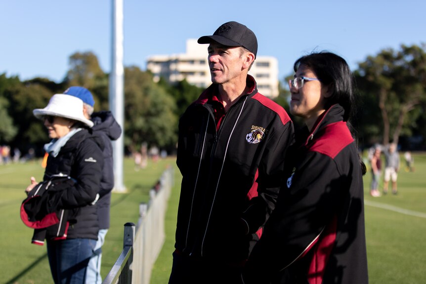 Subiaco AFC president Drew Palmer and team manager Caren Forlin on teh sidelines with spectators to their right.