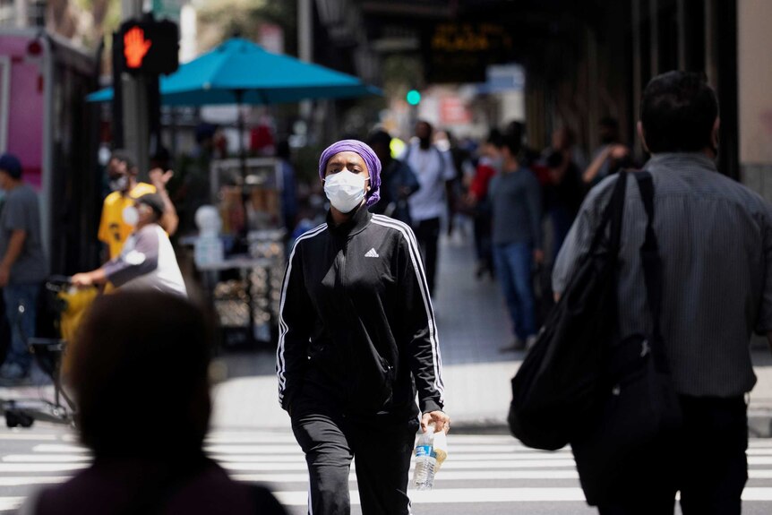 A pedestrian wearing a protective mask crosses the street during the outbreak of the coronavirus.