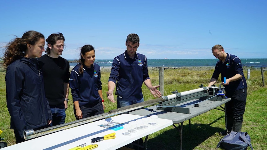 Peter Macreadie shows a group of bankers how to take a sediment core.