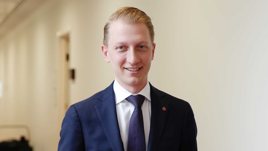 Senator James Paterson looks at the camera as he walks down a hallway at Canberra Parliament House.