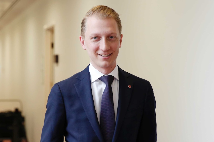 Senator James Paterson looks at the camera as he walks down a hallway at Canberra Parliament House.