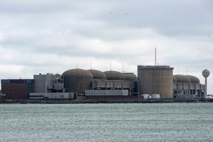 a nuclear generating station can be seen with water infront of it.