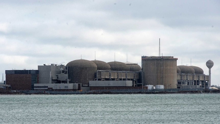 a nuclear generating station can be seen with water infront of it.