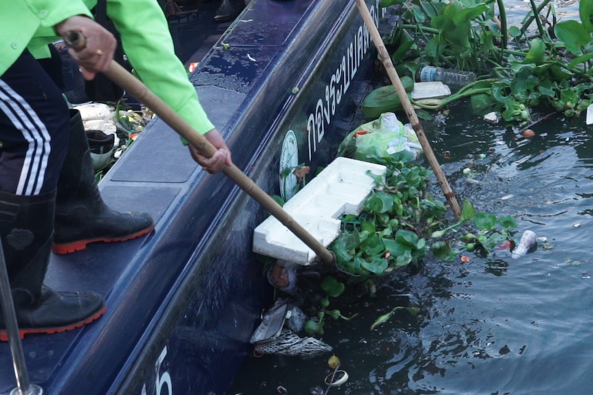 Plastic bottles and styrofoam is being fished out of the water with shovels.