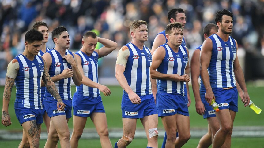 The North Melbourne Kangaroos look downcast as they walk off the field at Kardinia Park.