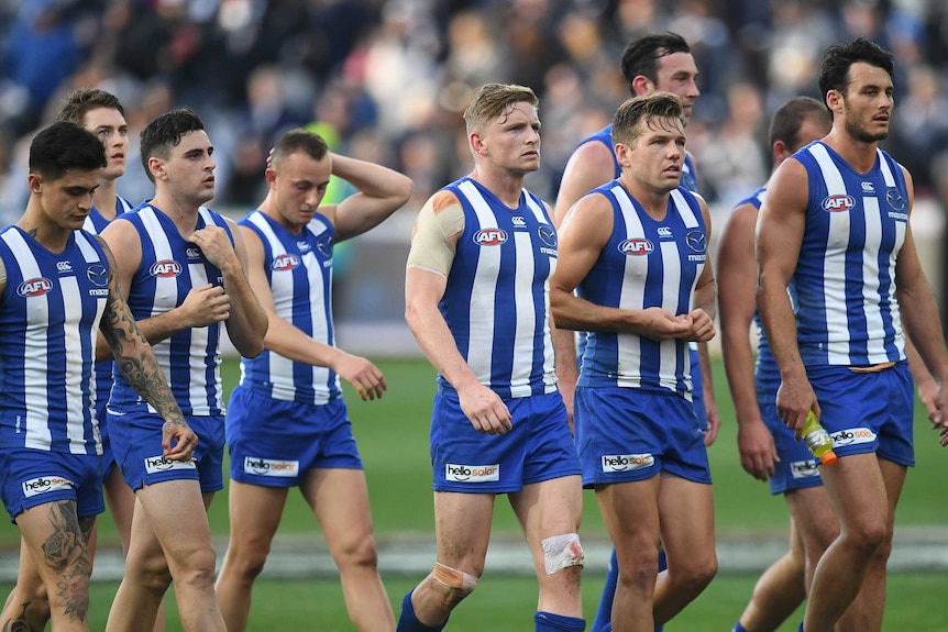 The North Melbourne Kangaroos look downcast as they walk off the field at Kardinia Park.