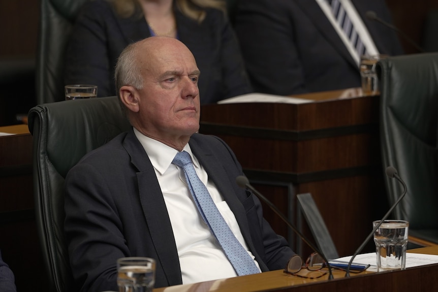 Eric Abetz looks downcast in a parliamentary chamber.