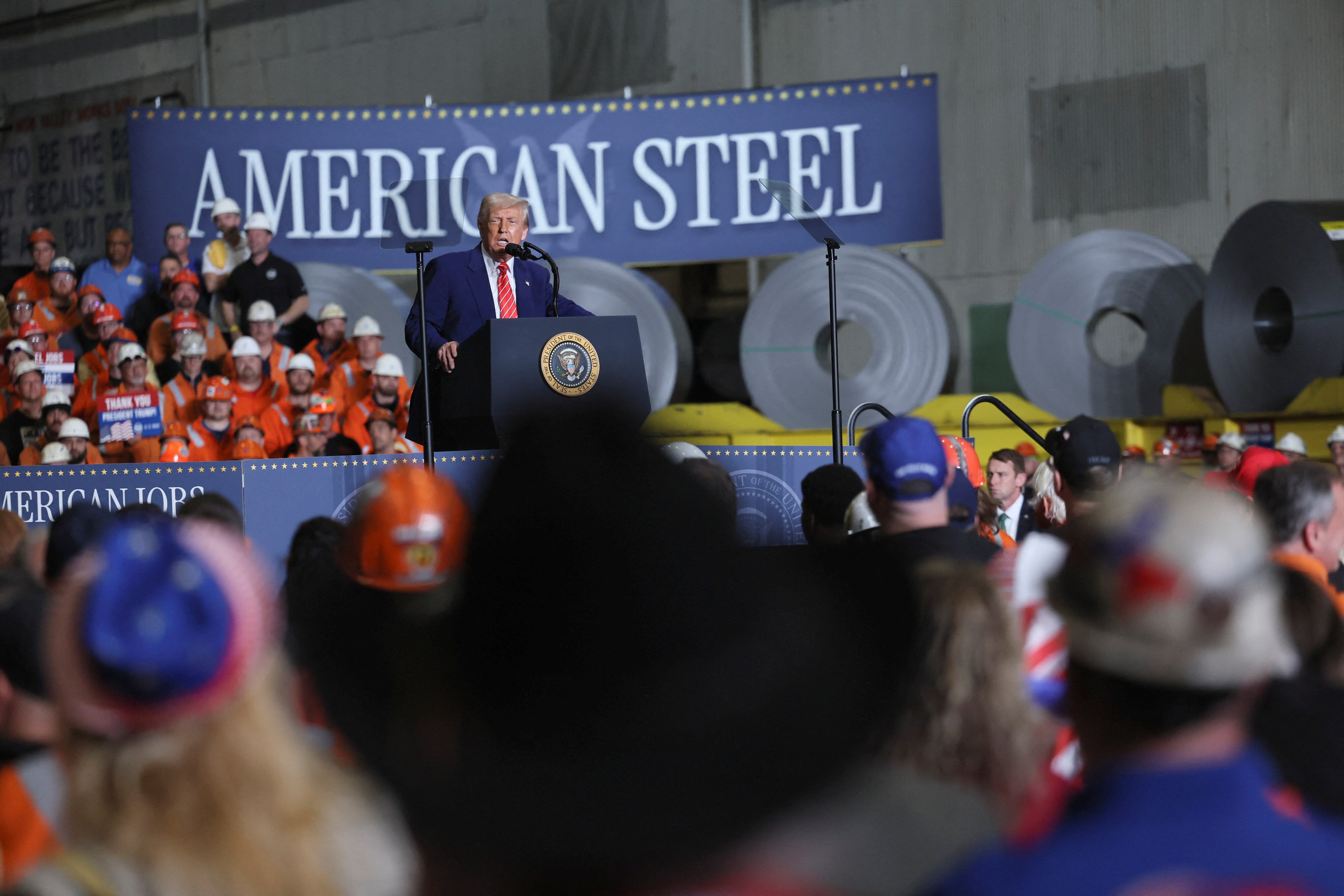 Donald Trump in front of a sign that reads American Steel.