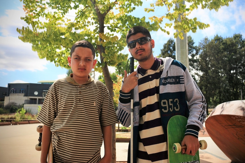 Two boys holding skateboards. 