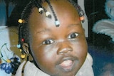 A tight shot of a smiling 15-month-old Sunday Mabior with her hair in braids.
