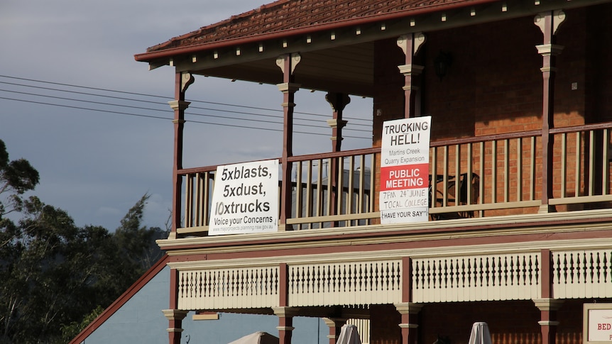 two anti quarry expansion signs displayed on the balcony of a building 