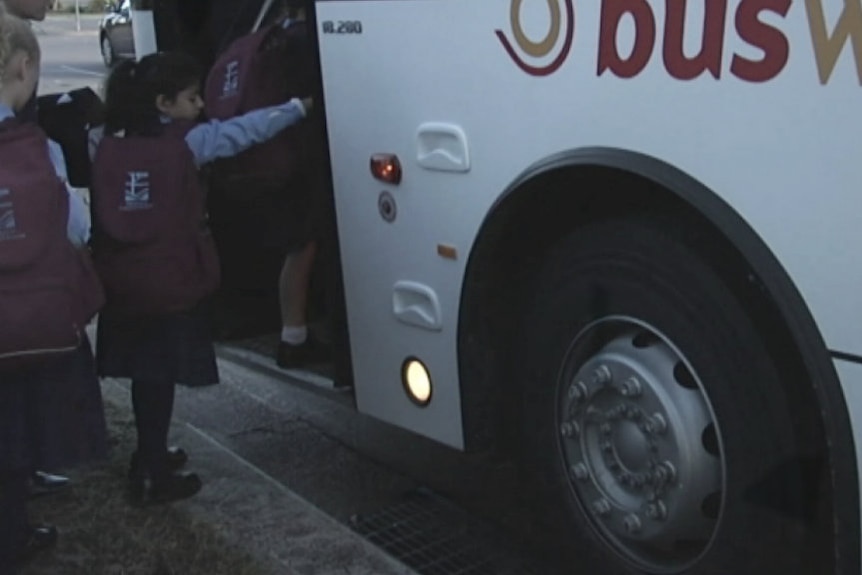 Young school children getting onto a bus.