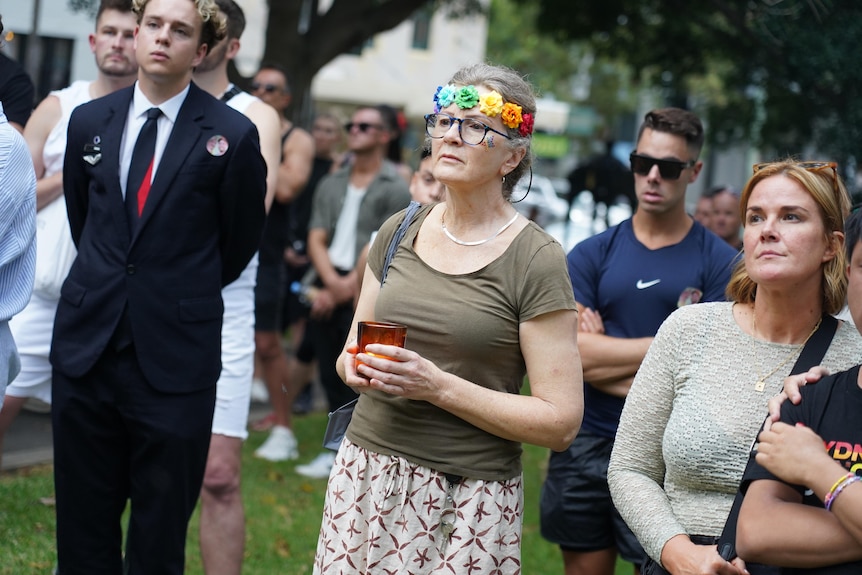 an elderly woman holds a candle at a vigil in darlinghurst for jesse baird and luke davies