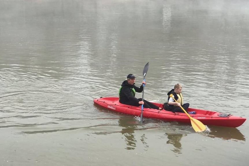 A boy and a girl ride in a canoe