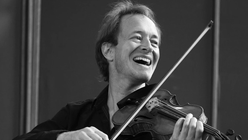 black and white photo of Anthony playing the violin and smiling broadly