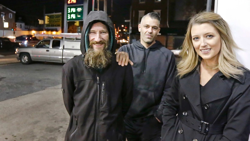 Closeup shot of Johnny Bobbitt Jr, left, with a big smile, with Kate McClure, right, and her boyfriend M'Amico in the centre.