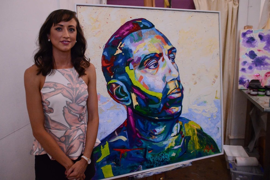 Darwin artist Rachel Adams with her portrait of Adam Goodes.