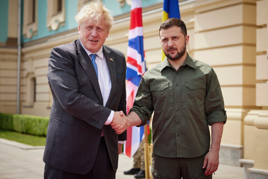 Two men shake hands for cameras.