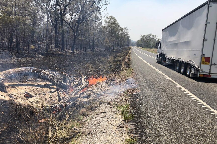 Fire still burning on the edge of the Bruce Highway, south of Mount Larcom.