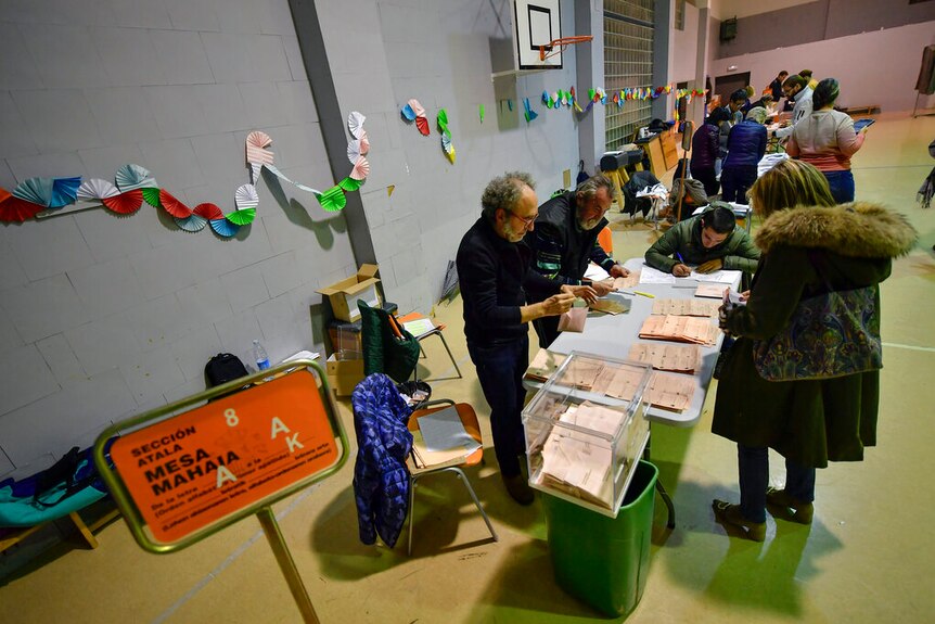 Election officials count votes at a polling station for the general election.