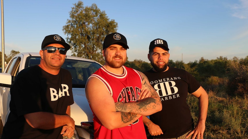 Three men lean on a car.